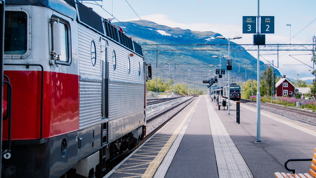 Foto eines Bahnsteiges, links der Wagon eines Zuges. Auf dem Bahnsteig sind weiße leitstreifen mit einem genoppten Bodenprofil, sodass sich blinde Personen daran orientieren können.